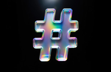 Symbole de mot-dièse (#) irisé sur fond noir, représentant un élément central de la communication digitale, de la mobilisation en ligne et du marketing sur les réseaux sociaux.